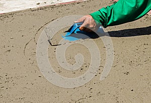 Close-up of hand using trowel to finish wet concrete floor