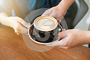 Close-up hand of a waitress serving a cup of coffee to customer.