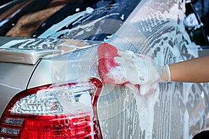 Close up hand wear gloves of hold sponge over the car for washing, Car wash service concept