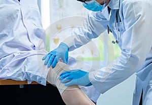 Close-up hand wear medical gloves doctor examining head of patient with knee problems in clinic