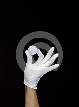 Close-up of a hand wearing a golf glove holding a golf ball between the fingers