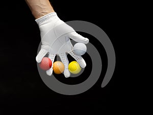 Close-up of a hand wearing a golf glove holding some golf balls between the fingers. Covid-19 concept