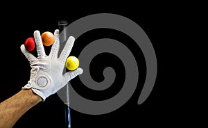 Close-up of a hand wearing a golf glove holding some golf balls between the fingers. Covid-19 concept