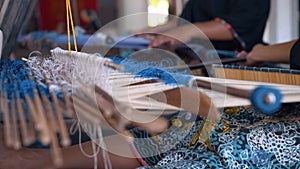 Close up of hand weaving with sticks, making traditional sarong in Indonesia