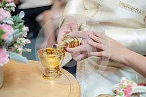 Close up of a hand wedding couple pour water of dedication, Thailand wedding