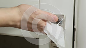 A close up of a hand wipes a door handle with wet napkin. Close up.