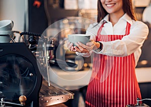 Close up hand of woman barista wear red apron holding hot coffee