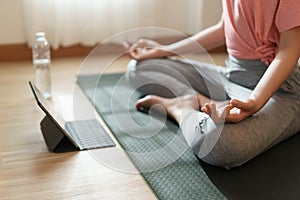 Close up of hand woman doing lotus yoga exercises on yoga mat with Training online on the tablet at home morning, Concept of