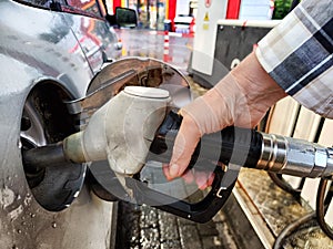 Close up of hand of woman holding gas gun while refueling car with gasoline. Filling fuel into tank of auto at gas
