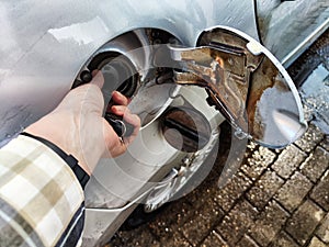 Close up of hand of woman holding gas gun while refueling car with gasoline. Filling fuel into tank of auto at gas