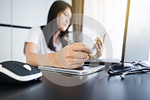 Close up of hand woman holding mobile phone with pen and using laptop for online shopping concept