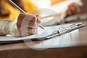 Close up hand of woman holding pencil thinking and writing data or business planning