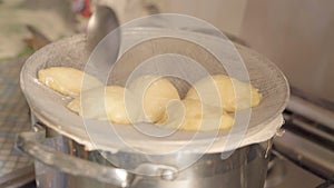 Close-up, hand of woman with spoon aid take take-on piro patties and lay them in a metal bowl