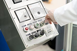 Close-up of hand of woman turning on an industrial machine with