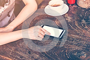 Close up of hand woman using phone in coffee shop with Vintage t