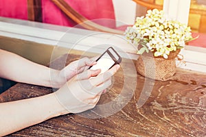 Close up hand woman using phone in coffee shop with vintage tone