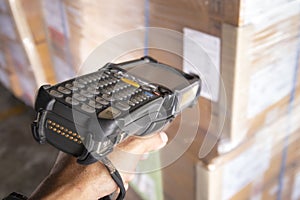 Close-up, hand of worker holding barcode scanner scanning cargo boxes. Computer equipment for warehouse inventory management.