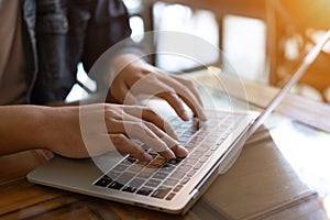 Close up hand is working on his laptop at cafe. Hand is typing keyboard on laptop.