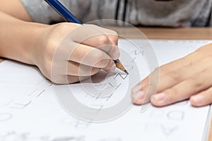 Close up hand writing homework on wooden table at home. Kid learing and writing alphabet photo