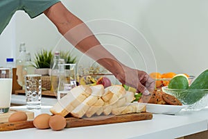 Close-up hand young asian man reaching for cookie placed in plate on kitchen table, grabbed a cookie ate it pick up glass milk