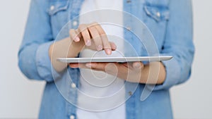 Close up on the hand of young handsome woman pointing and touching the screen of a tablet with her finger. technology