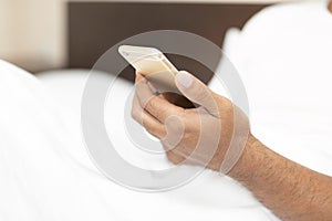 Close up hand young man cell phone addict man awake at morning in bed