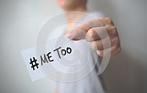 Close up hand of young man holding show a white card with word â€œMe Tooâ€. Social movement concept
