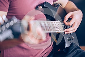 Close up hand of young man playing on a professional, black electric guitar, music instrument, entertainment, lifestyle