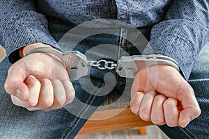 Close-up of handcuffed hands. The value of the security. Insulation. The handcuffs are locked.