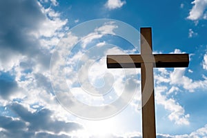 close-up of a handheld wooden cross against a bright sky