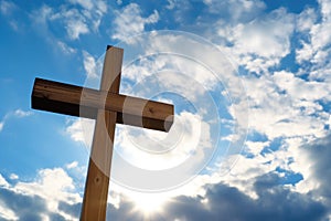 close-up of a handheld wooden cross against a bright sky