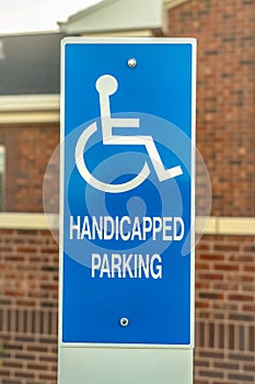 Close up of Handicapped Parking sign against blurred red brick wall of church