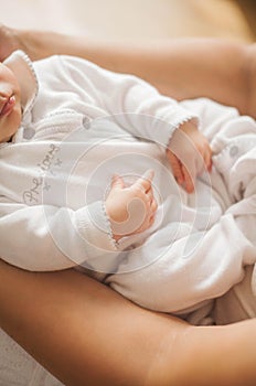 Close-up. The handle of the baby in mother`s hands. Cute newborn baby sleeping in mother`s arms. Motherhood