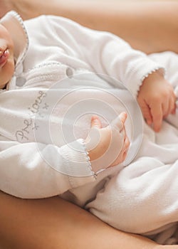 Close-up. The handle of the baby in mother`s hands. Cute newborn baby sleeping in mother`s arms. Motherhood