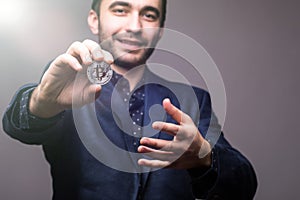 Close up of Handome business man pointed bitcoin on camera on dark background with tonned light