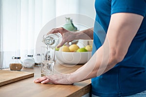 Close up hands of active strong man pouring clean water into glass. Attractive thirsty male drink or take a sip of mineral natural