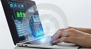 Hands typing on laptop displaying complex data charts and code on screen for analysis