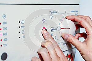 Close up hands adjust settings on washing machine