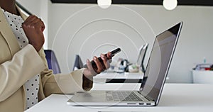 Close up of hands of African American businesswoman sitting at desk using smartphone