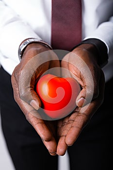 Close-up. Hands of an African American male doctor cardiologist with a red heart. Health care