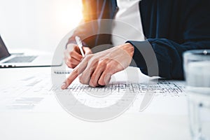 Close-up of hands architect uses laptop and building blueprint on working table in office space