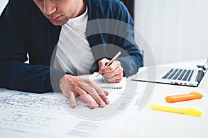 Close-up of hands architect uses laptop and building blueprint on working table in office space