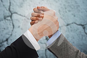 Close up of hands arm wrestling over concrete wall