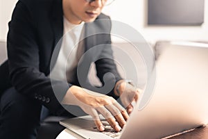 Close up hands of Asian business man using laptop computer working from home sitting on sofa, new normal  digital lifestyle, work