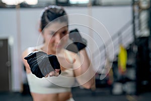 Close up hands of Asian woman action of puch and hit also look at camera with smiling in fitness gym