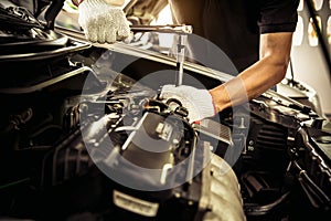 Close-up hands of auto mechanic are using the wrench to repair and maintenance auto engine