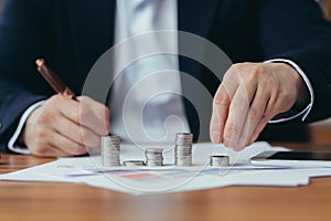 Close up hands of a banker businessman counting coin money, and making calculations