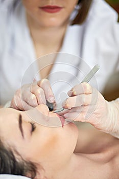 Close-up hands of beautician doing epilation on photo