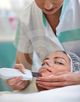 Close up of hands of beautician making cavitation treatment on human face