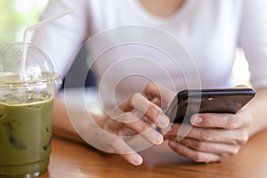 Close up hands of beautiful young woman holding mobile, smart phone sitting in cafe. Soft focus hands of women holding and use